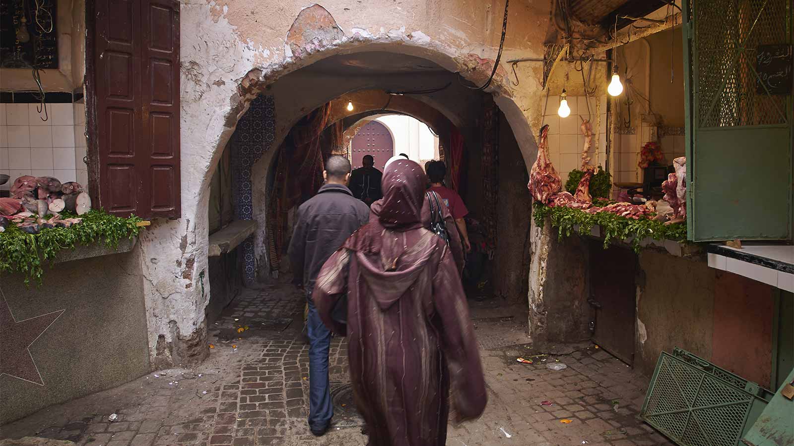 Visitors walking through a traditional archway inside Marrakech’s old Medina.